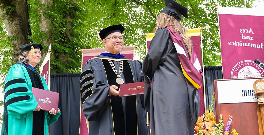 President Menjares shakes hands with a student at SPU